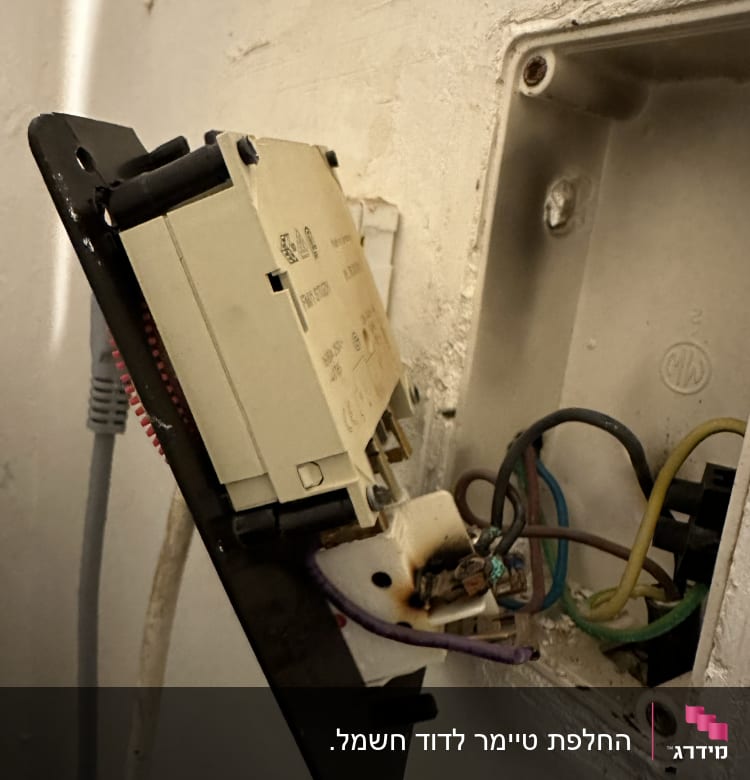 חוטי חשמל חשופים בקופסת חיבורים בקיר